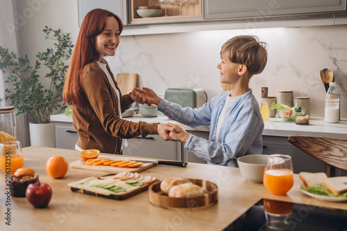 Mother and son dance together while holding hands at kitchen 
