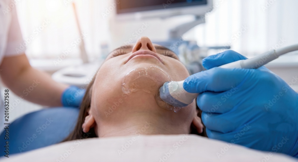 Fototapeta premium Cosmetic ultrasound treatment on patient's jawline