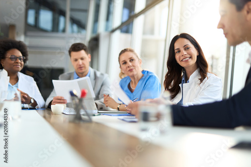 Female doctor talking to her colleagues during a meeting with their administrator in hospital.