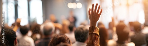 One person raises hand in a blurred audience at a bright event