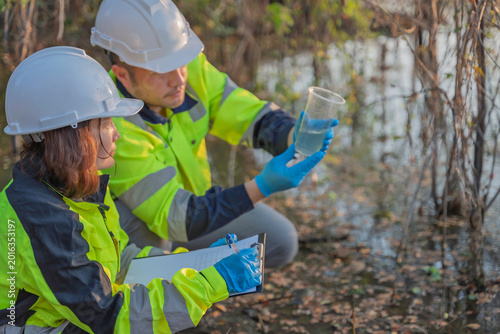Quadro em tela Environmental engineers collect water samples from a swamp for quality testing