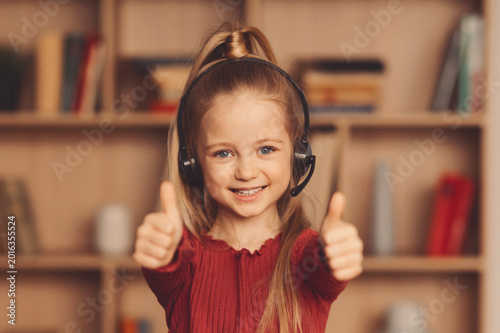 Fotografie A girl with long hair smiles while giving two thumbs up