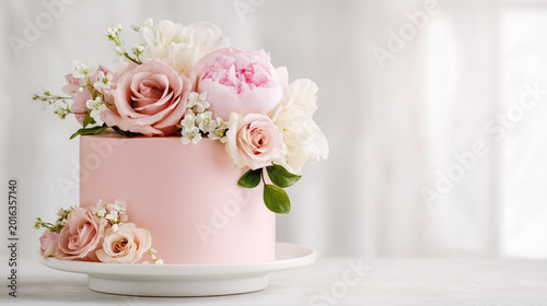A pink cake decorated with fresh flowers, a floral pastry celebration