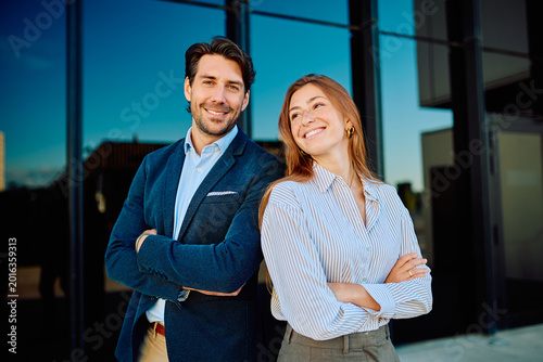 Foto Professional man and woman standing back to back, arms crossed, smiling, represe