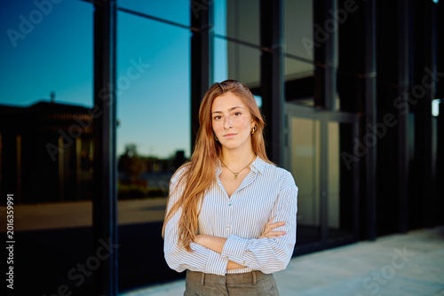 Quadro su tela Young businesswoman with freckles and long red hair standing confidently against