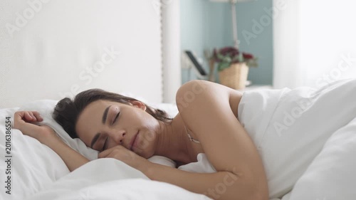 Happy woman enjoying warm morning atmosphere while lying in bed. Concept self care and cozy lifestyle.
