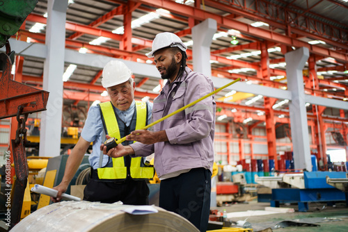 Factory workers inspecting industrial material and construction plans