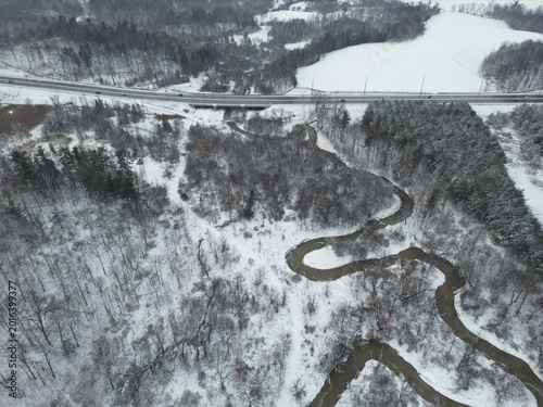 Aerial view of a meandering river in a snow-covered landscape with a road in the background - Vue aérienne des méandres d'une rivière dans un paysage enneigé avec une route en arrière-plan