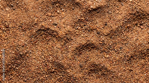 Close-up full frame view of rough dry sandy terrain featuring small pebbles and irregular patterns, showcasing the natural texture and earthy tones of the ground material