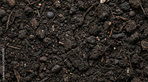 Close-up of dark, rich, and fertile garden soil, showcasing its earthy texture with visible organic matter and small stones