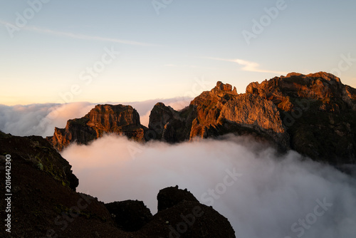 Obraz na płótnie majestic mountain peaks surrounded by clouds at sunrise under a clear blue sky