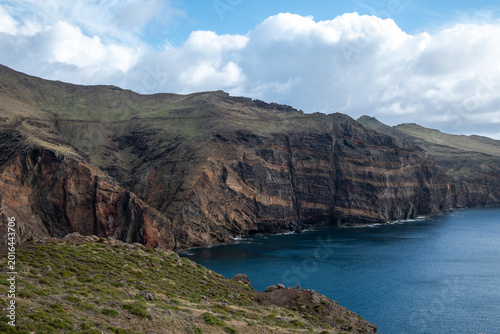 Foto rocky coastal cliffs under a partly cloudy sky meeting the clear ocean water on