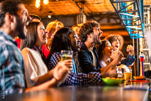 Diverse friends cheering loudly after soccer goal in pub
