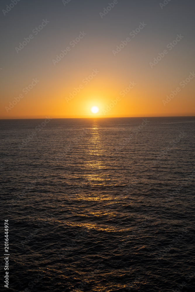 Obraz premium breathtaking ocean sunset casting warm hues over tranquil sea horizon at evening twilight
