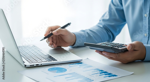 Accounting and finance professional working on a laptop with a calculator and financial reports, demonstrating financial analysis and business management