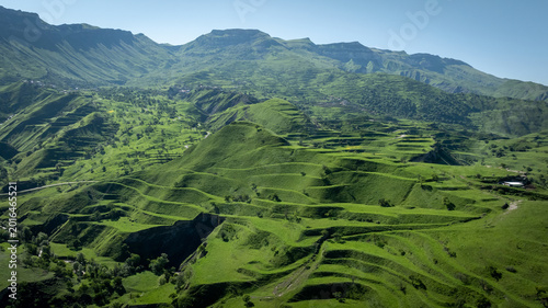 Wide panoramic landscape of the Chokh agricultural terraces on lush green hills and ridges near Kommuna, Dagestan, Russia, on a clear sunny day