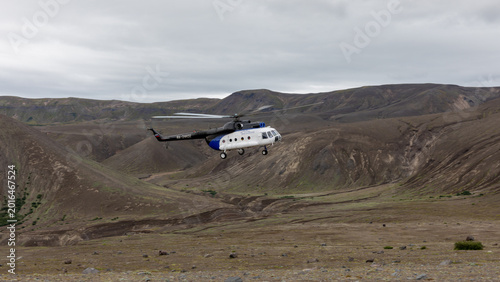 Quadro su tela White helicopter flying above the rugged volcanic caldera of Ksudach, with barre