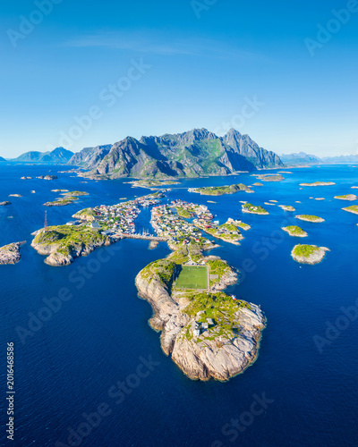 Aerial drone view of Henningsvaer village in Lofoten islands, Norway. Famous view of the football field and the fishing village. Scenic summer travel and arctic nature in Scandinavia.