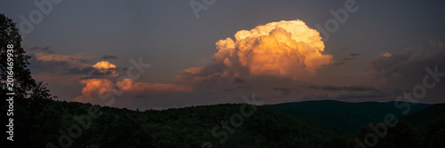 Bild auf Leinwand Panorama Of Distant Thunder Head Catching The Fading Sun Light