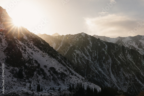 Foto Scenic winter landscape with sun rays over rugged snowy Tian Shan peaks and dark