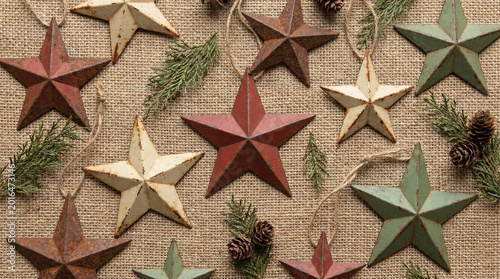 Vintage Metal Stars Scattered on Burlap Fabric Flat Lay. Overhead arrangement of aged tin star decorations on natural burlap texture, rustic holiday styling