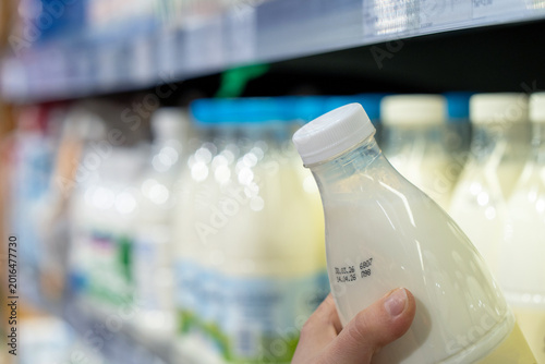 Εκτύπωση καμβά Womans hand holding milk bottle in supermarket