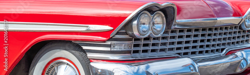 Closeup of red vintage car headlight and radiator. Front of old car. Veteran car details.
