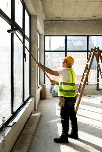 Man Painting Windows in a Building Under Construction During Daytime