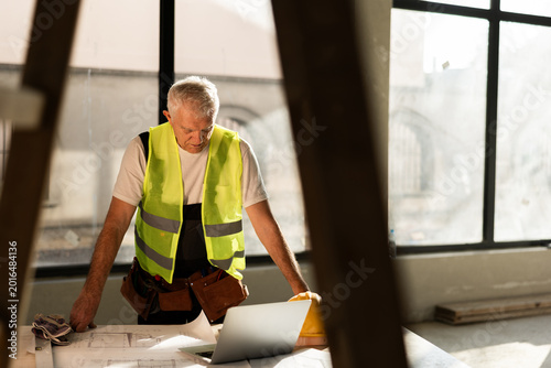 Construction Worker Reviews Plans at a Desk During the Day Inside a Building Site