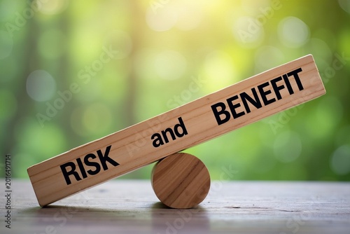 Balancing Risk and Benefit: A Symbolic Photo of a Seesaw on a wooden plank with risk and benefit inscribed on either end
