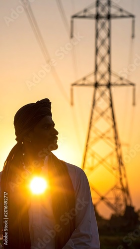 A silhouette of a man in front of a power tower at sunset