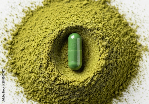 Green herbal powder surrounds a single green capsule on a white background
