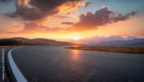 Empty winding asphalt road leading into the horizon at sunset.