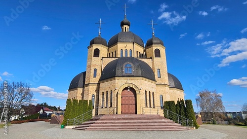 Fotografie Front view of a modern brick Eastern Orthodox church with black domes and crosse