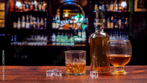 Tableau sur toile Whiskey Glass, Brandy Snifter and Bottle on Irish Pub Bar