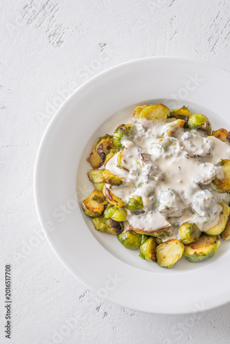 Roasted Brussels sprouts with creamy blue cheese sauce in white bowl