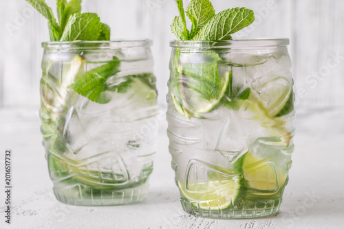Two fresh mojito cocktails in tiki glasses with lime mint garnish