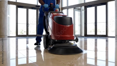 Janitor using a floor scrubber machine in a lobby