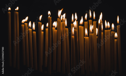 Quadro em tela Burning taper candles illuminating darkness at memorial