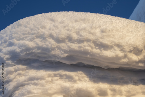 A snowdrift of white snow against a blue sky.