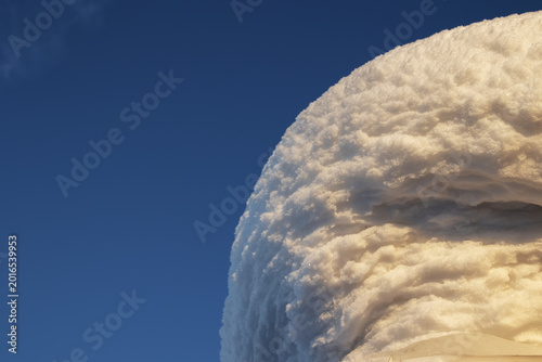 A snowdrift of white snow against a blue sky.