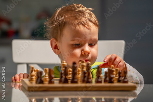 Schilderij op canvas Little grandmaster concept with child moving chess pieces thoughtfully
