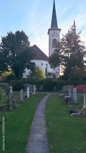 Church pathway through historic cemetery landscape during peaceful evening season, spiritual architectural perspective with memorial grounds, symbolic Christian heritage atmosphere for reflection