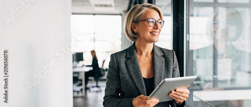 confident businesswoman using tablet in modern office with natural light