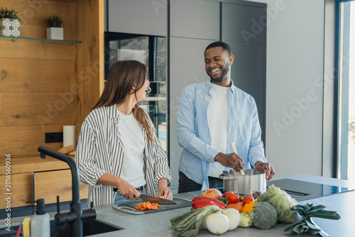 Photos Enthusiastic multi-ethnic couple sharing a lighthearted moment while preparing f