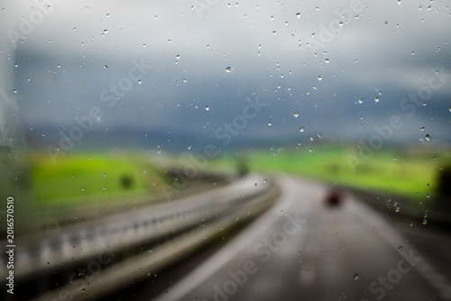 Window pane with raindrops and out of focus view of a motorway and countryside in the interior of Sicily between Syracuse and Catania, Sicily, Italy
