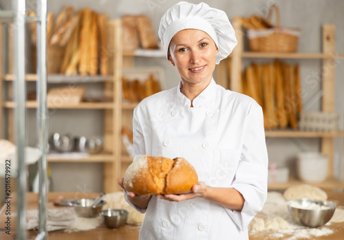 Fotografija Bakery woman employee holds ready-made loafs of breads