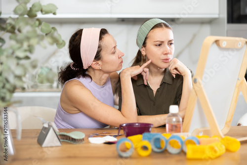 Foto Adult and young women looking in mirror in kitchen at home..