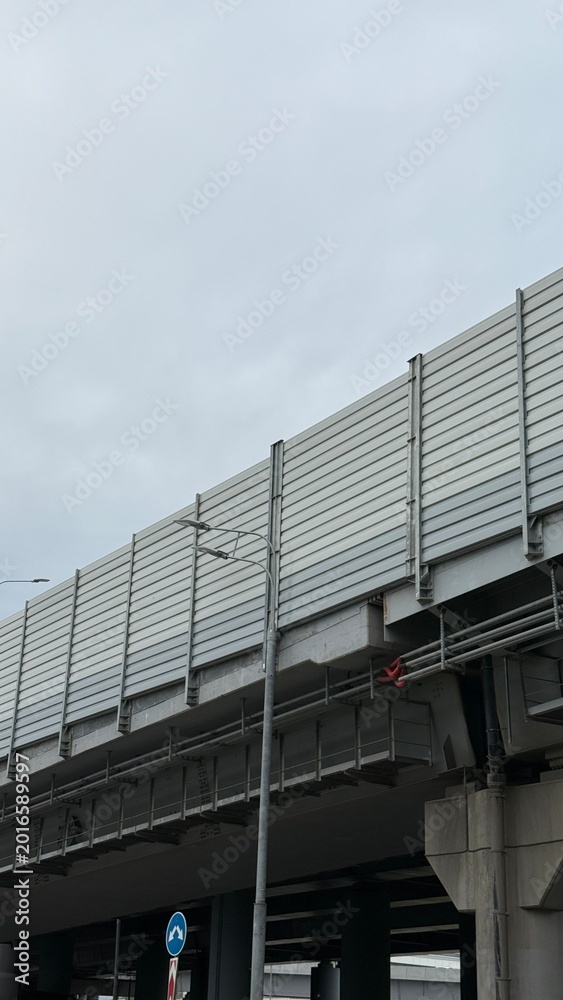 Obraz premium Modern elevated highway structure with sound barrier panels and urban infrastructure under cloudy sky