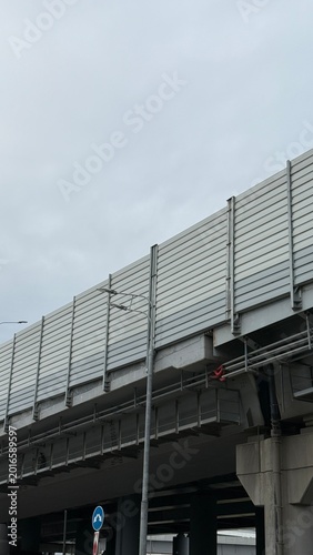 Modern elevated highway structure with sound barrier panels and urban infrastructure under cloudy sky